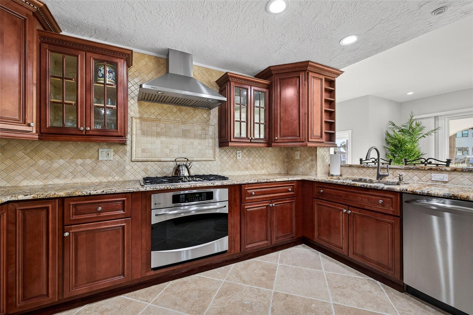 Efficient GE Profile appliances including gas cooktop, convection microwave, electric oven and gas oven, commercial ice maker, and wine fridge. Kohler fixtures and granite countertops.