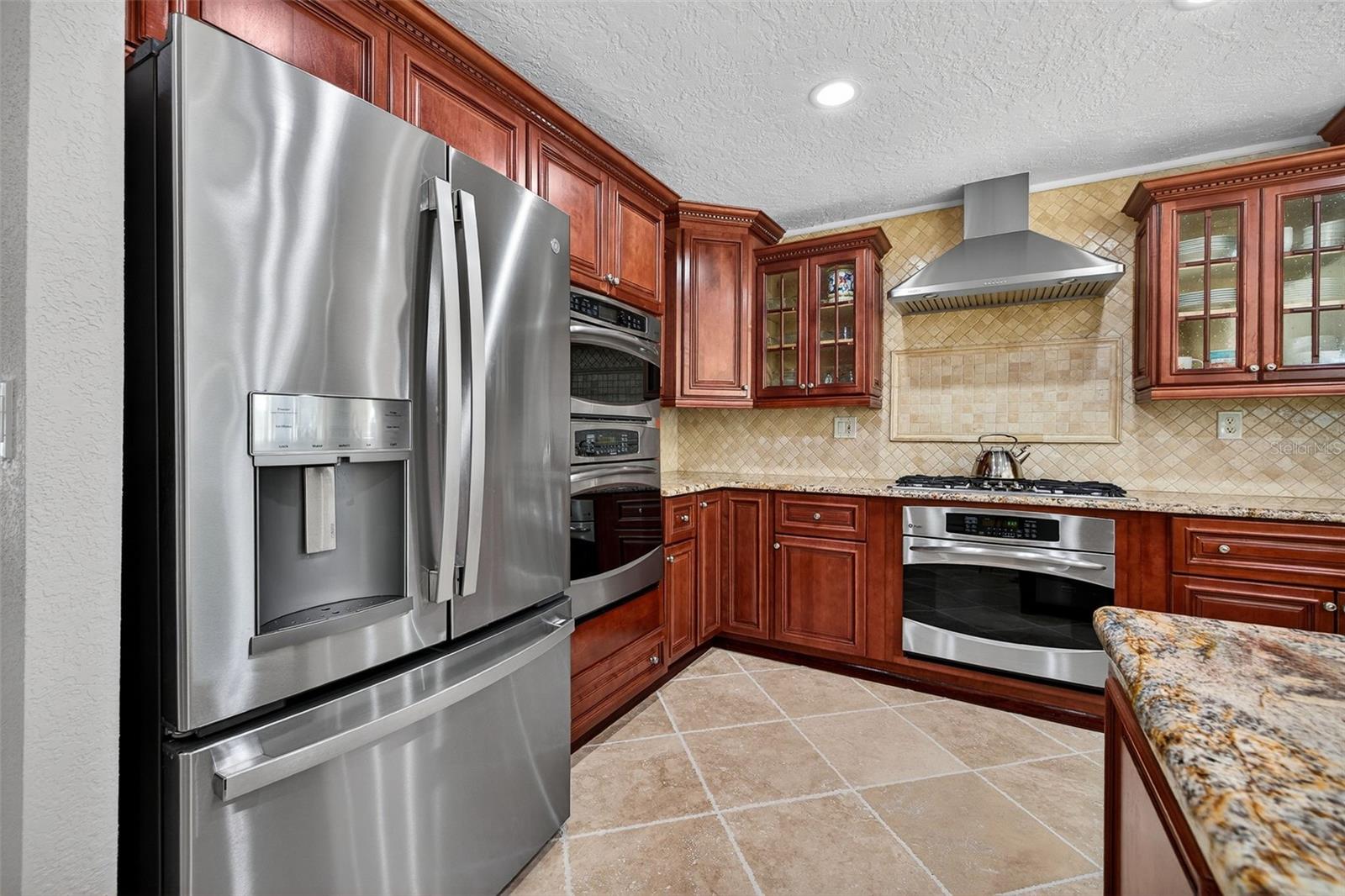 Efficient GE Profile appliances including gas cooktop, convection microwave, electric oven and gas oven, commercial ice maker, and wine fridge. Kohler fixtures and granite countertops.