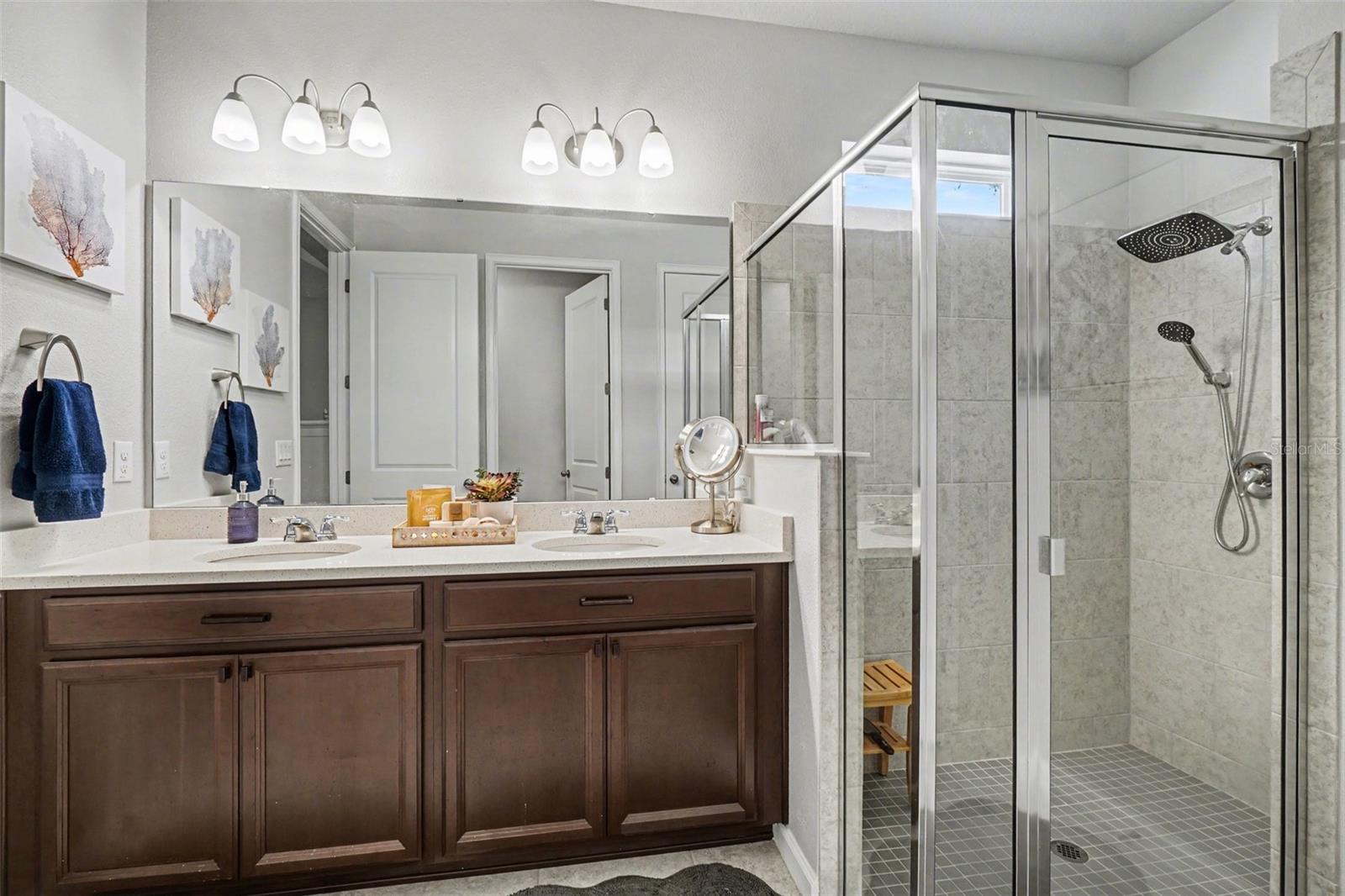 The primary bathroom features dual vanities, a tiled walk-in shower, a separate toilet area, and a large linen storage space.