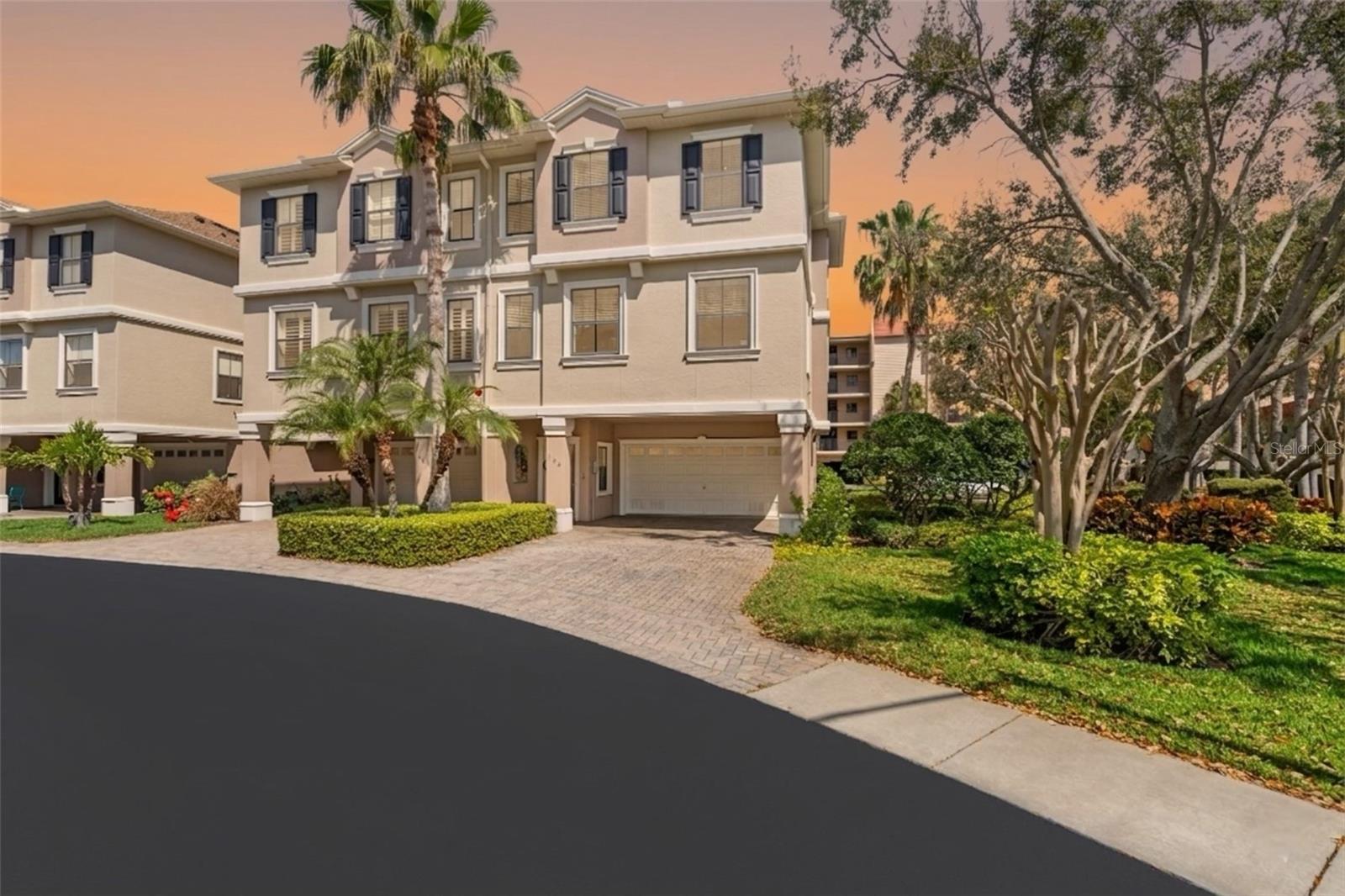 Well-maintained building surrounded by mature palms and manicured greenery, creating an inviting and picturesque approach.