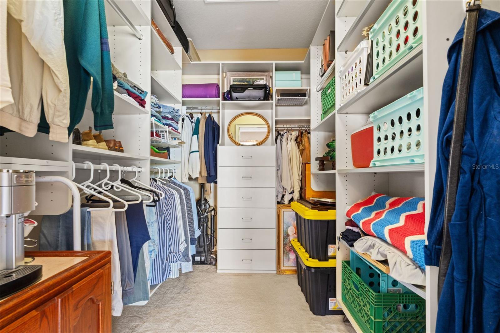 Spacious walk-in closet with custom shelving, built-in drawers, and ample hanging space for organized storage.
