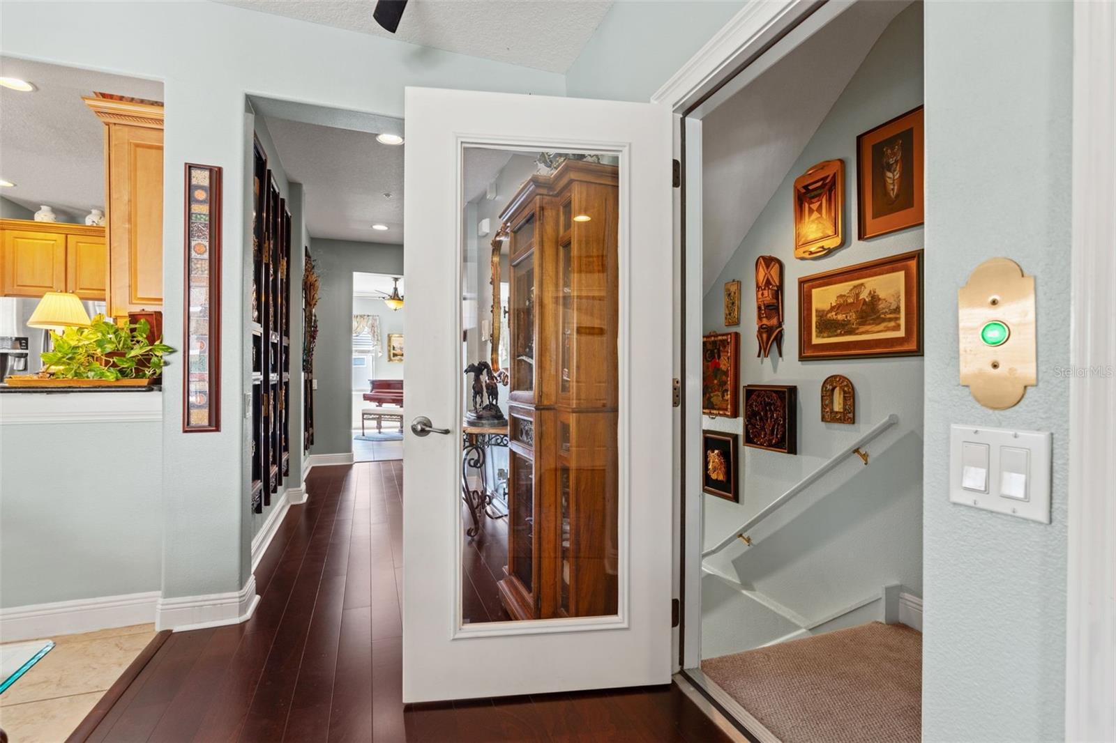 Bright interior entry featuring a decorative glass-paneled door, wood flooring, and access to the upper level via a carpeted staircase.