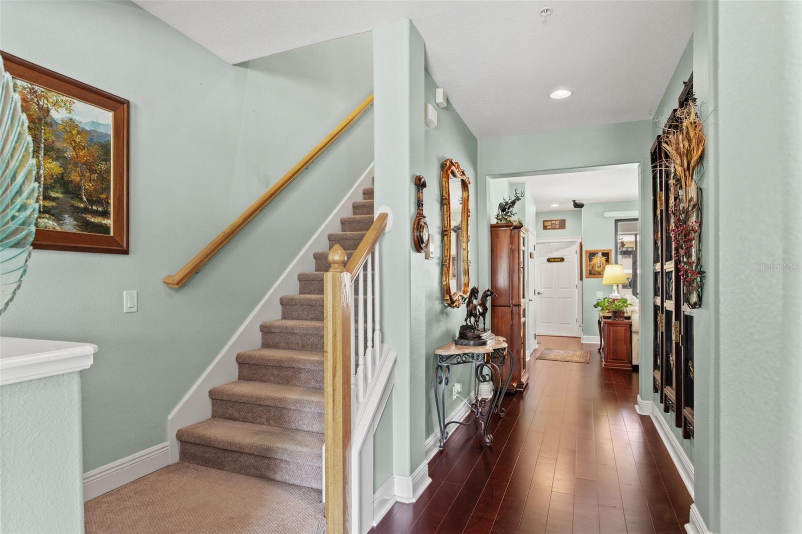 Spacious hallway with rich wood flooring, elegant decorative accents, and staircase access creating a welcoming transition to the main living areas.