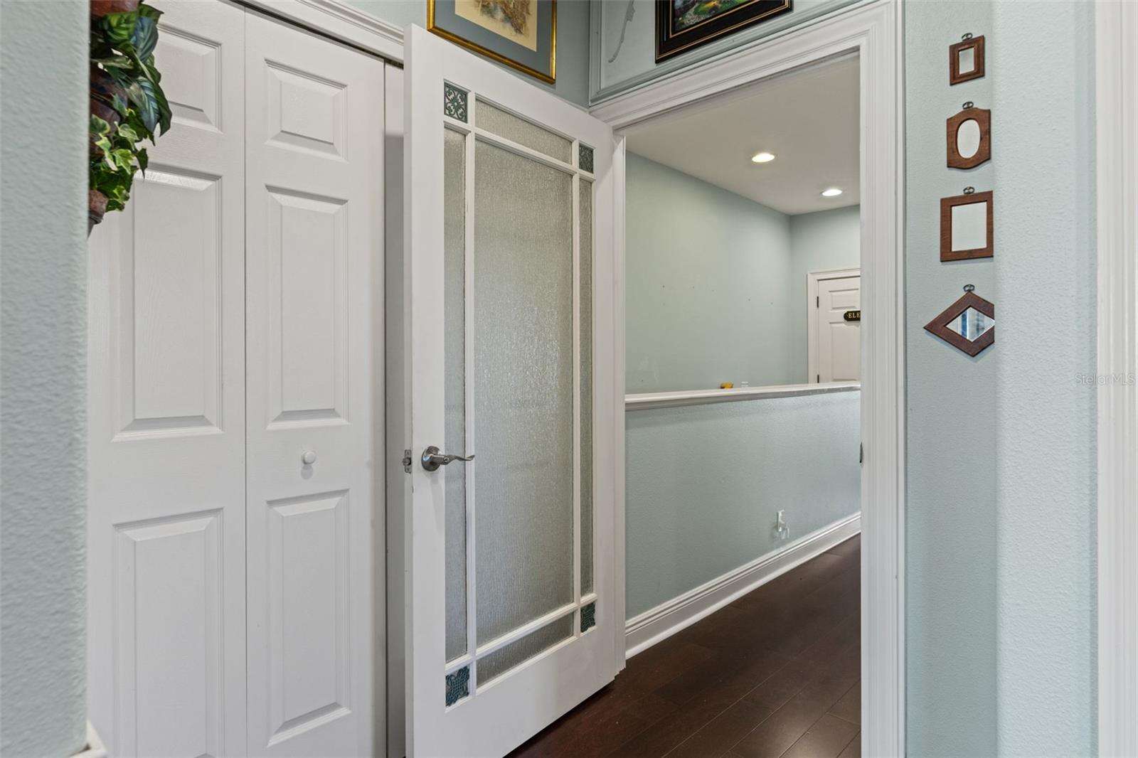 Bright hallway featuring wood like flooring, decorative trim, and access to additional rooms.