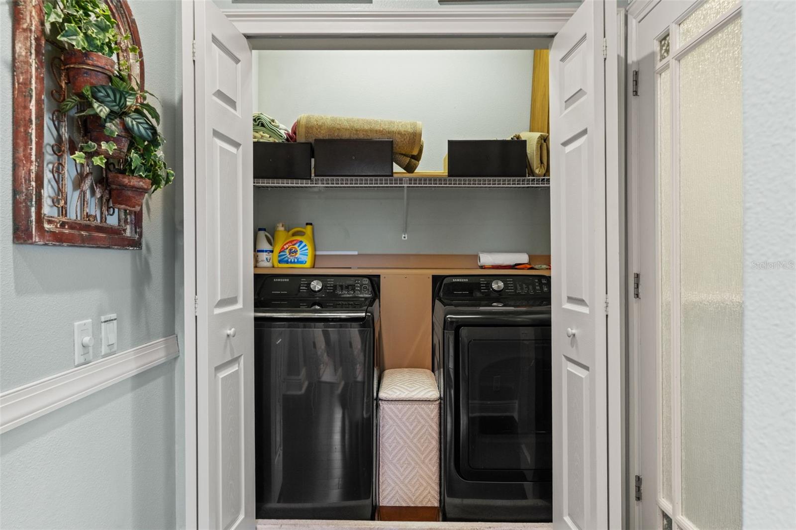 Convenient in-unit laundry closet with full-size washer and dryer and overhead shelving for supplies and linens.