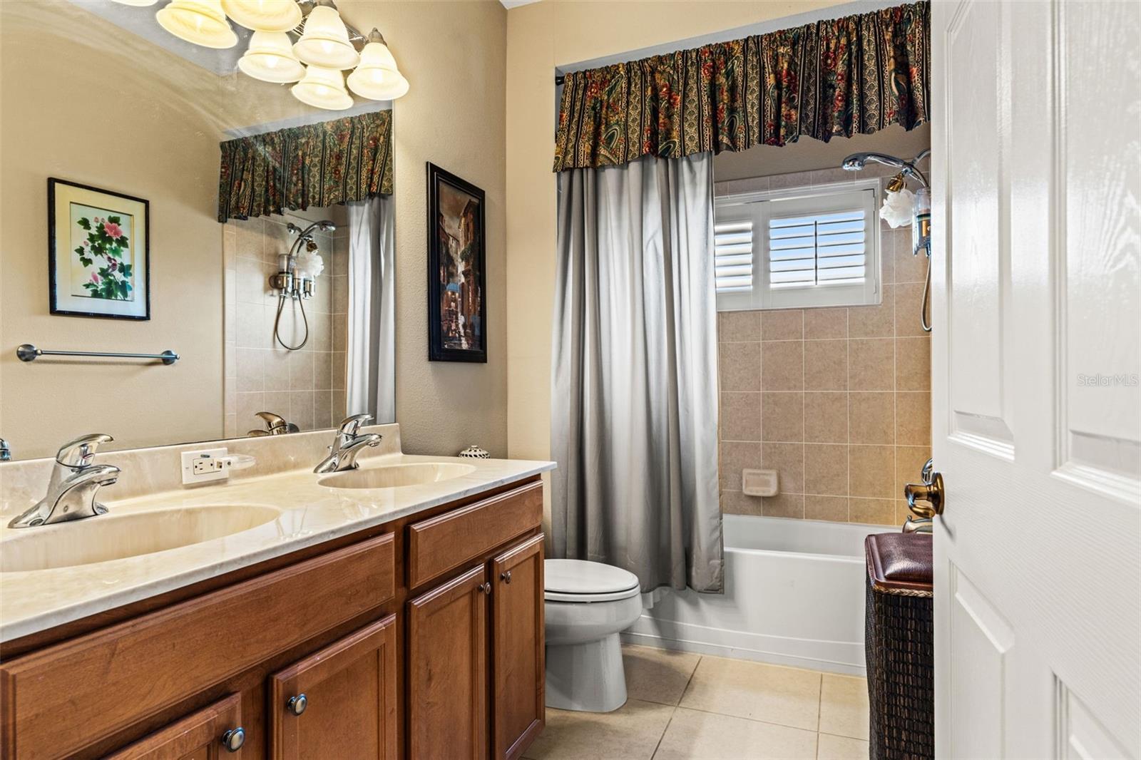 Full bathroom with dual-sink vanity, ample cabinet storage, and a tub/shower combination.