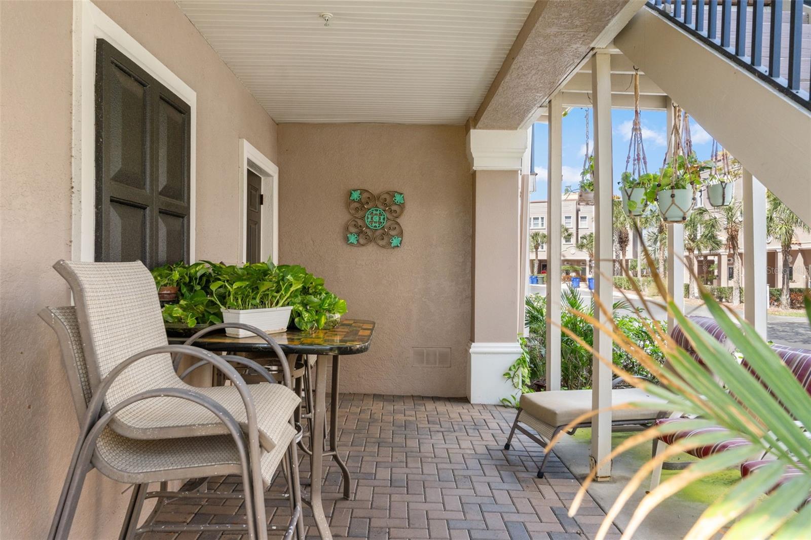 Inviting covered patio with brick paver flooring and space for seating, perfect for relaxing and enjoying the surrounding tropical landscaping.