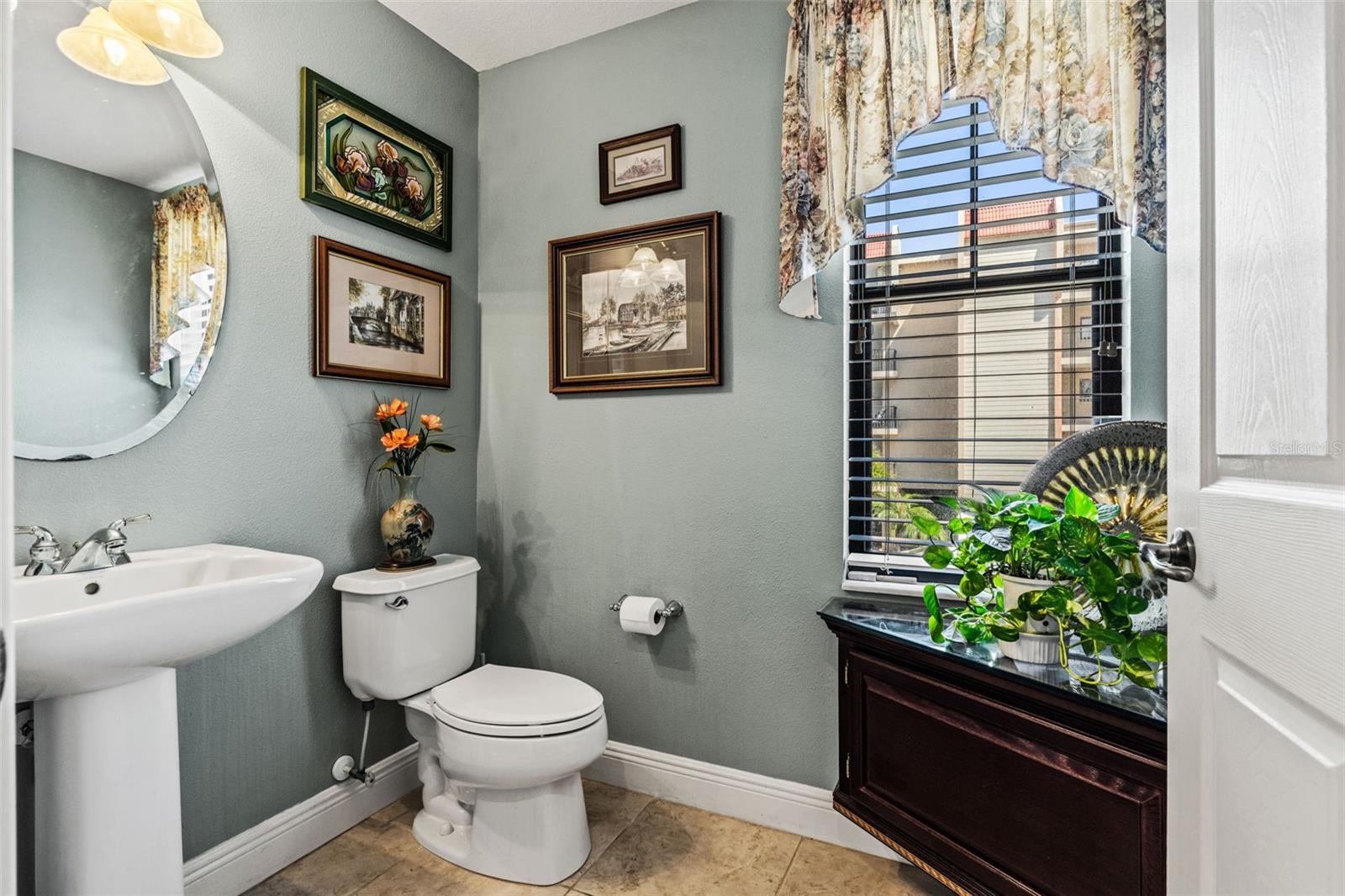 Charming half bath with pedestal sink, decorative accents, and a window providing natural light.