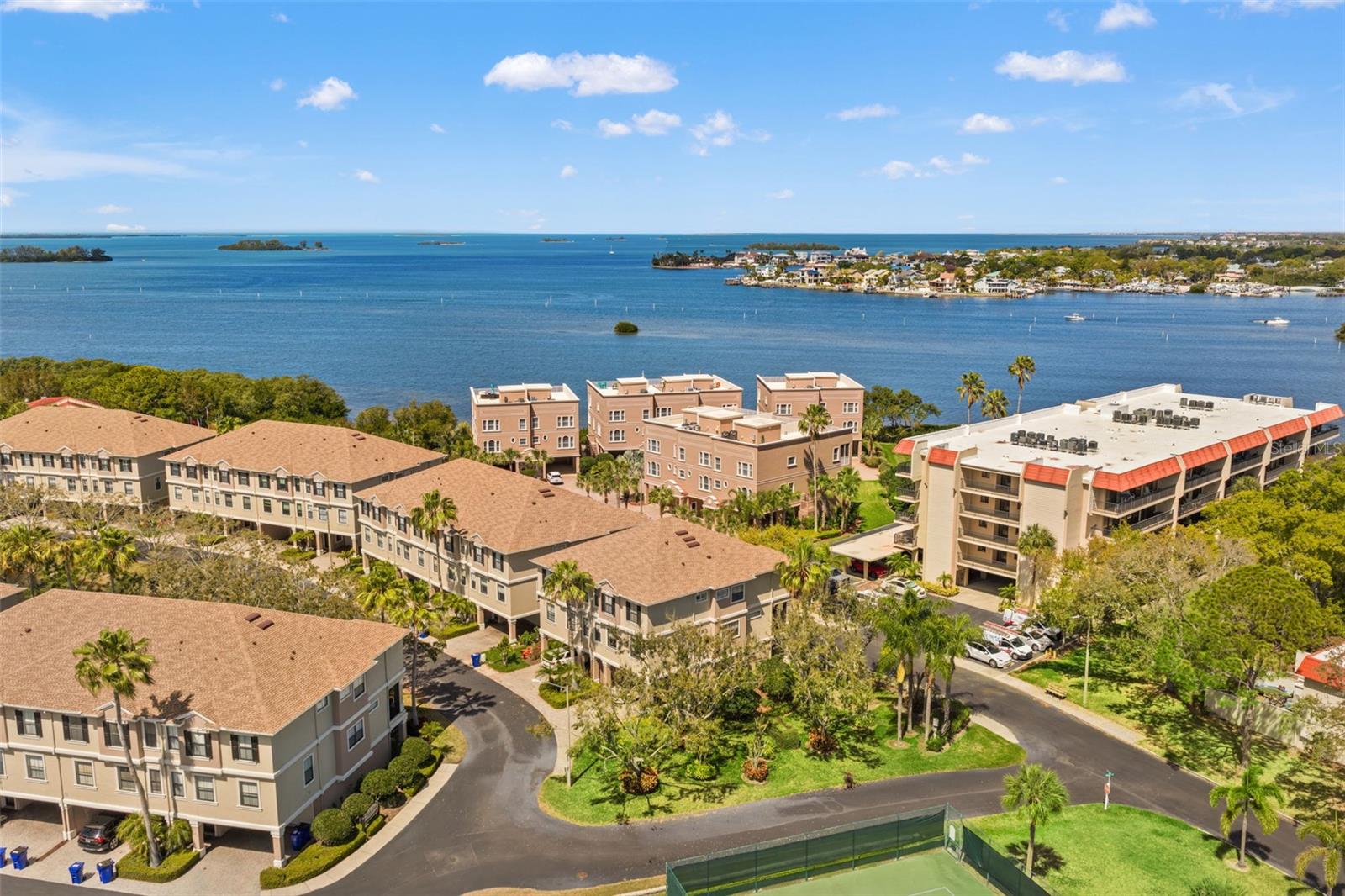 Elevated aerial perspective showcasing the surrounding community, lush landscaping, and nearby waterfront views.