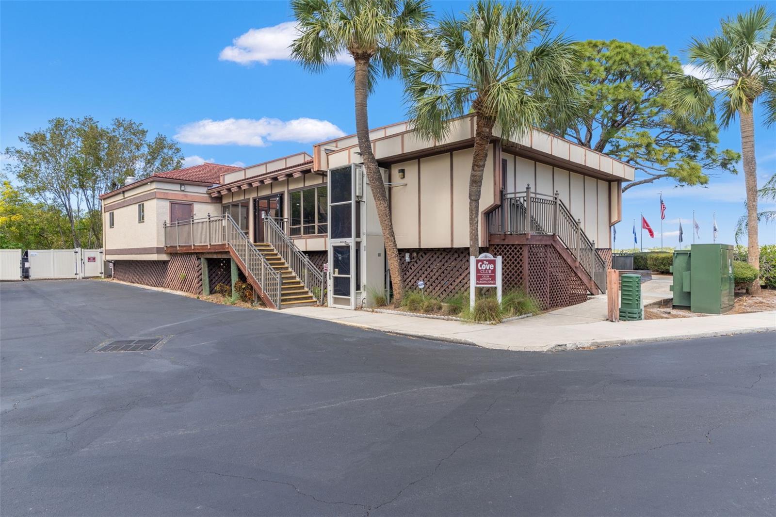 Community clubhouse surrounded by tropical landscaping and palm trees, offering gathering and recreation space for residents.