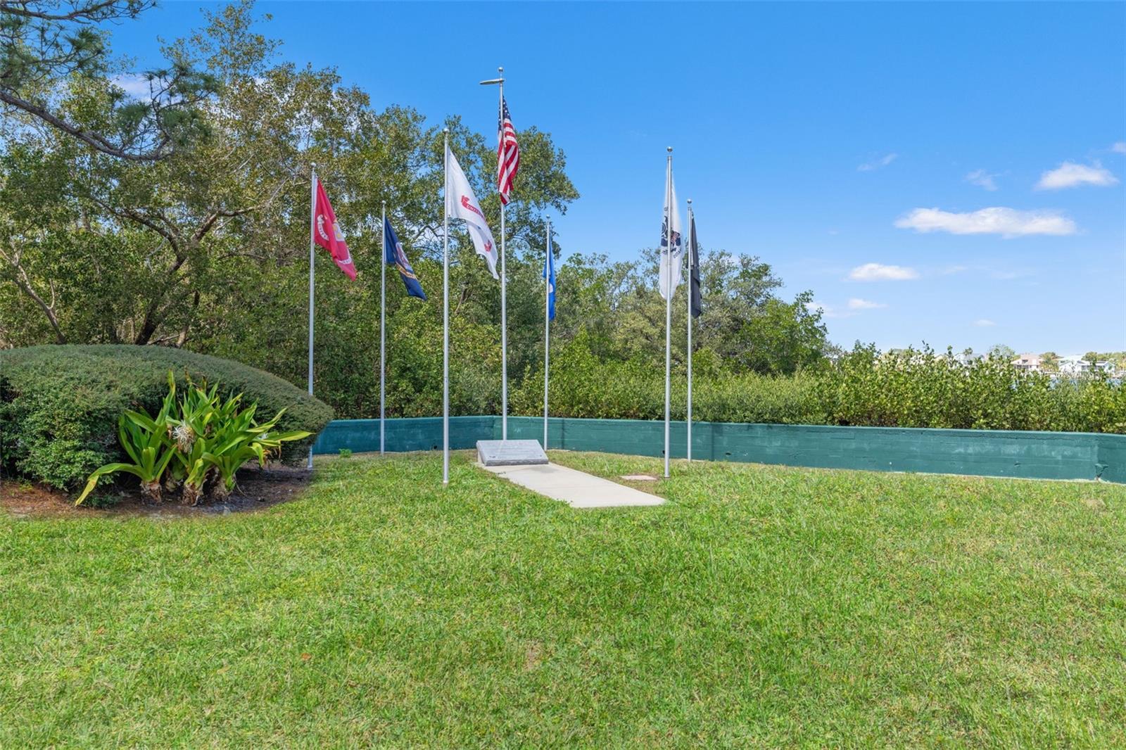 Landscaped memorial plaza featuring flagpoles and green space, providing a peaceful outdoor setting within the community.