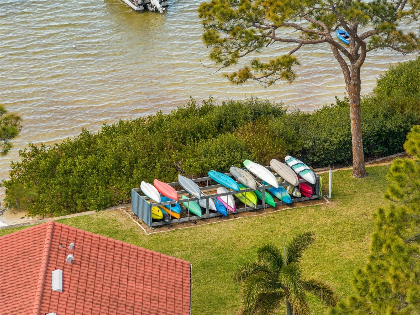 Community waterfront area with storage racks for kayaks and paddleboards, perfect for enjoying the nearby waterway.