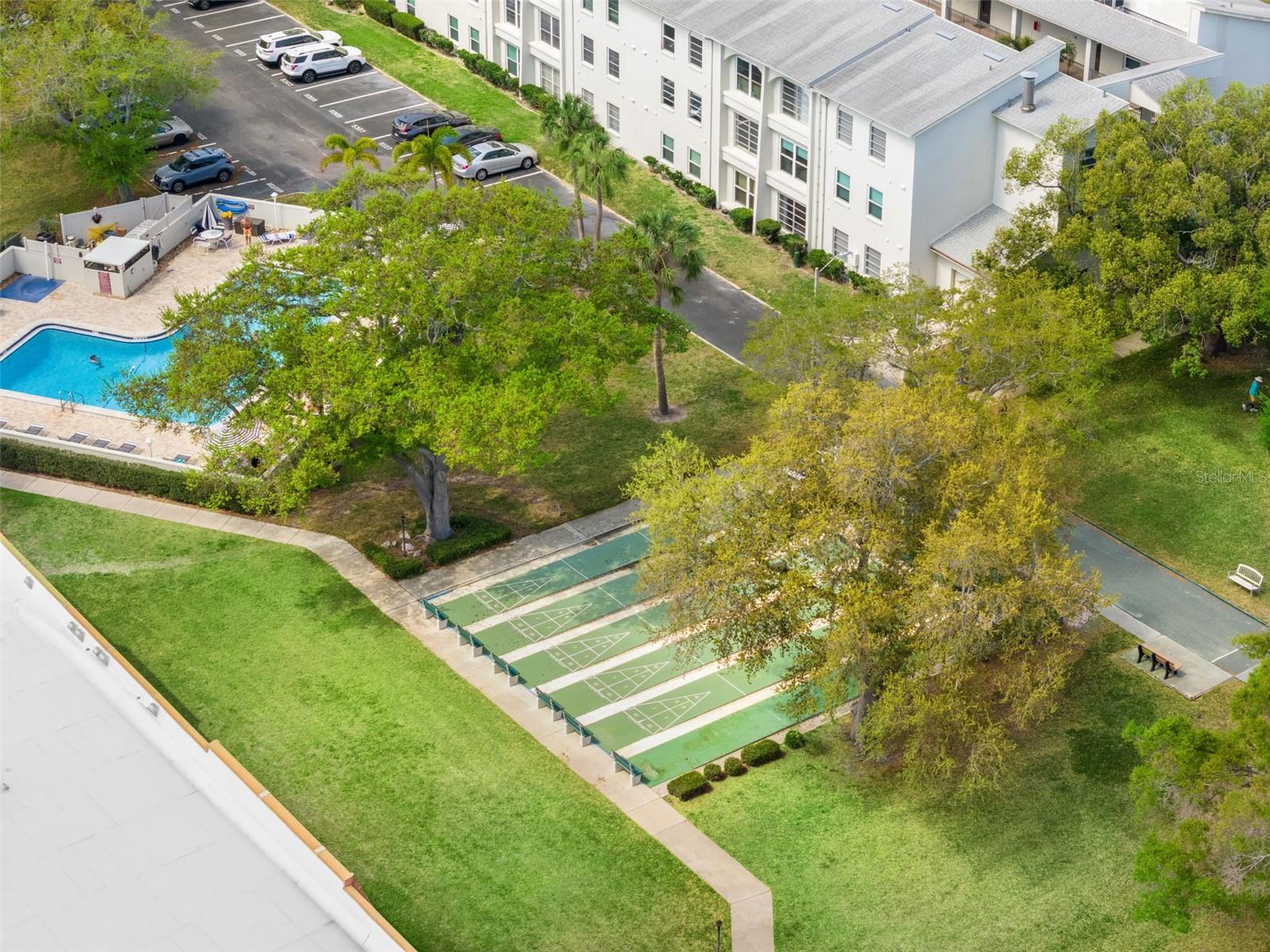 Community shuffleboard courts set among mature trees and green space for outdoor recreation.