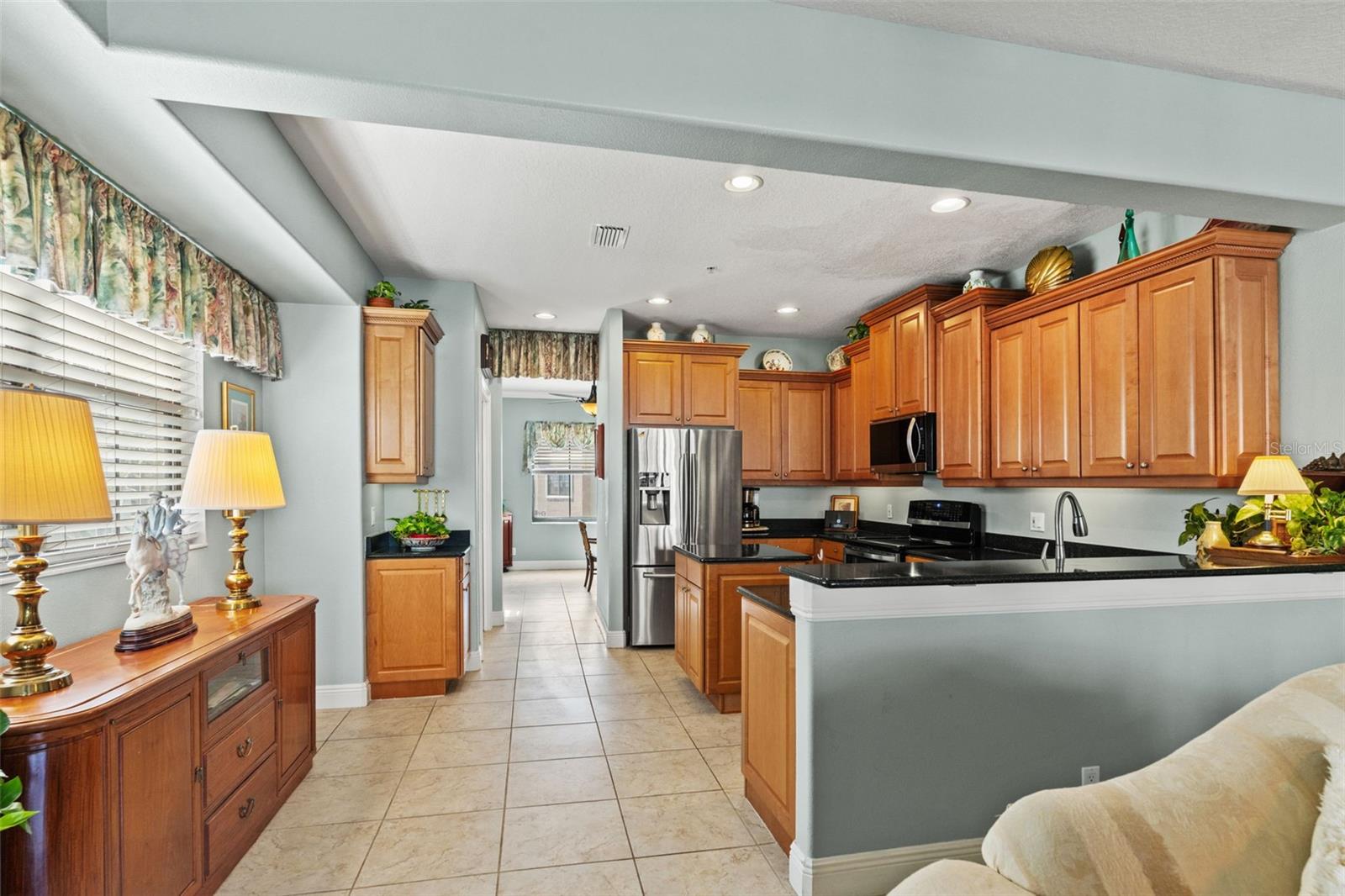 Bright and functional kitchen featuring abundant wood cabinetry, granite countertops, stainless steel appliances, and a convenient breakfast bar.