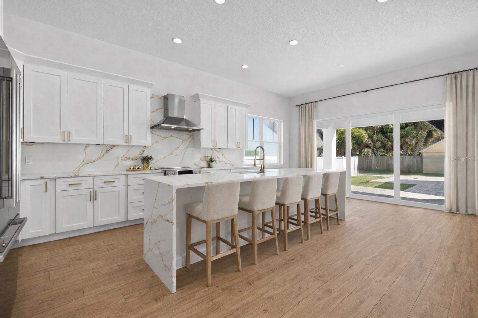 Generous kitchen with waterfall quartz countertop island.