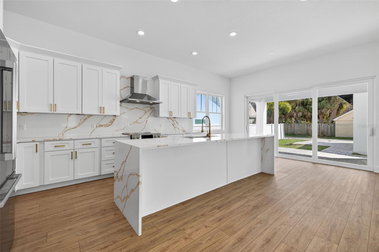 Generous kitchen with waterfall quartz countertop island.