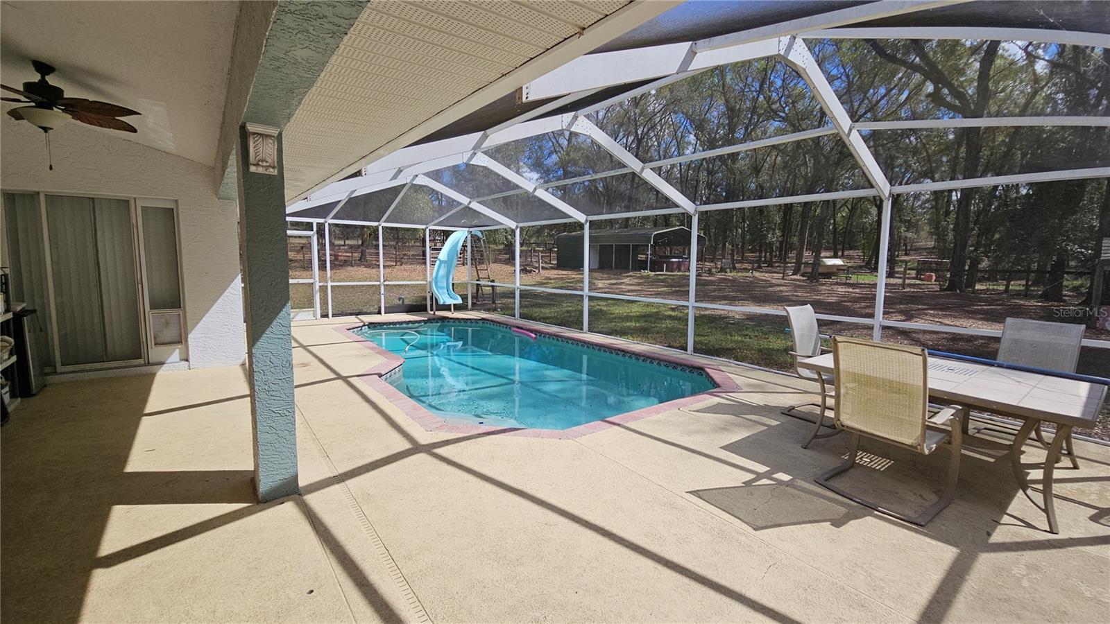 Screened-in Pool with slide and covered lanai with views of the backyard