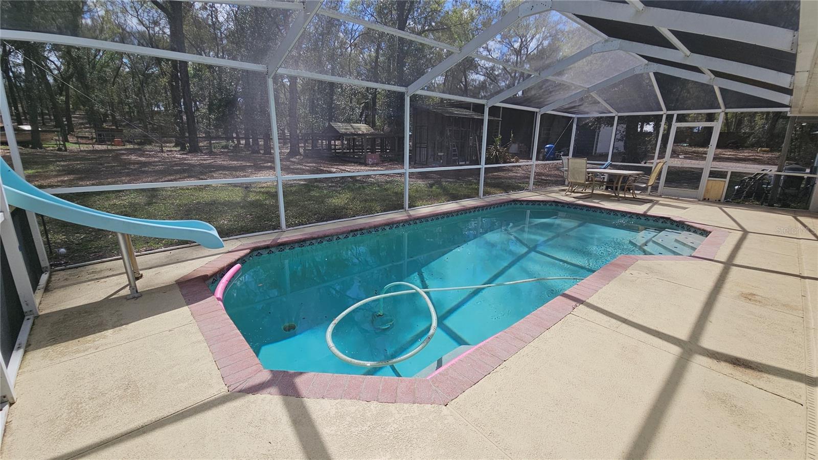 Screened-in Pool with slide and covered lanai with views of the backyard