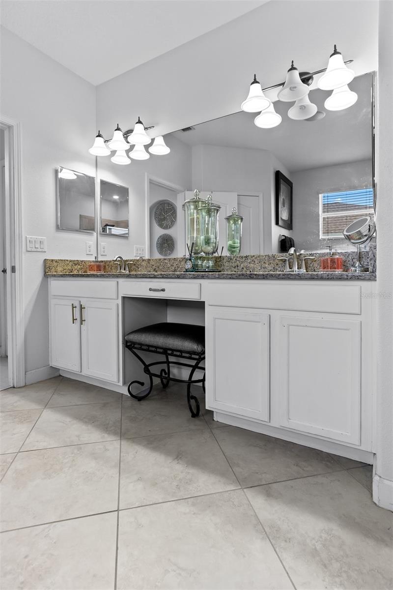 Bright master vanity with double sinks, granite tops, and designer light fixtures.