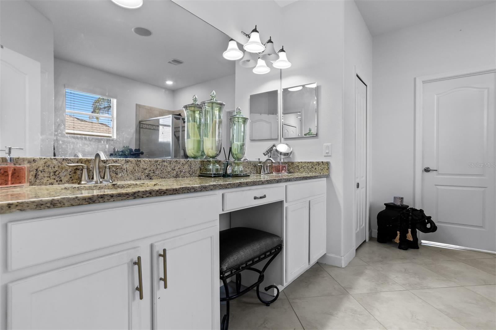 Expansive primary bathroom with double sinks, granite counters, and dedicated makeup vanity.