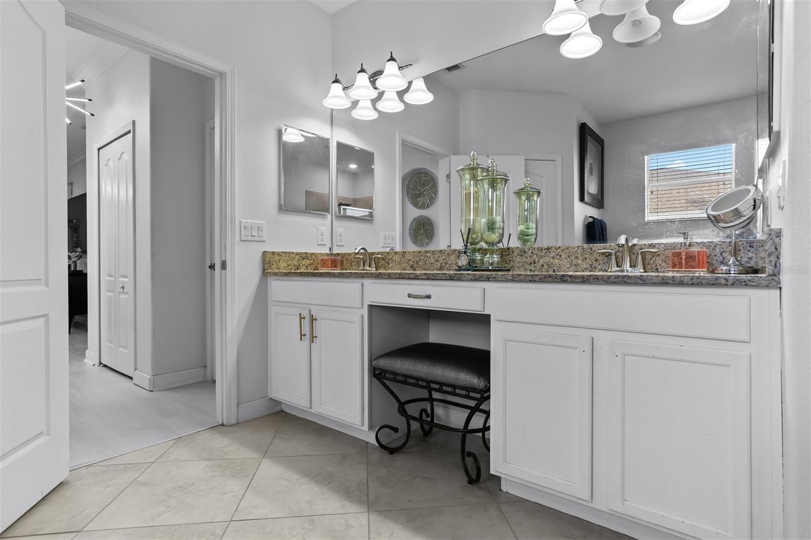 Wide view of the primary en-suite vanity showing the makeup station and storage.