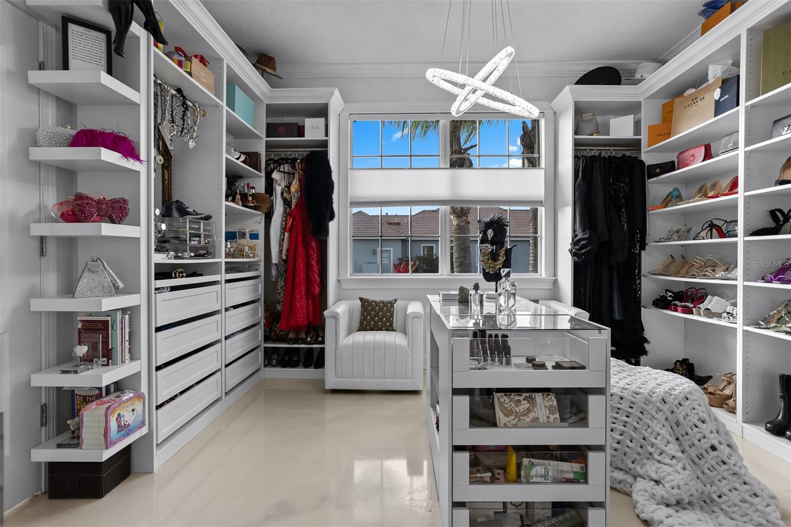 Massive custom-built walk-in closet with center island, glass displays, and designer lighting.