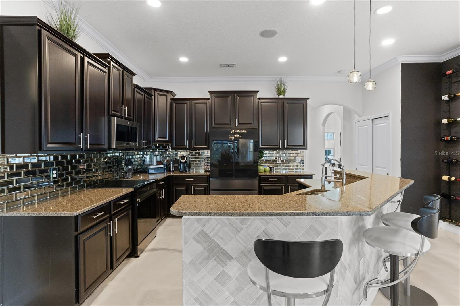 Gourmet kitchen with espresso cabinetry, granite counters, and herringbone tile backsplash.