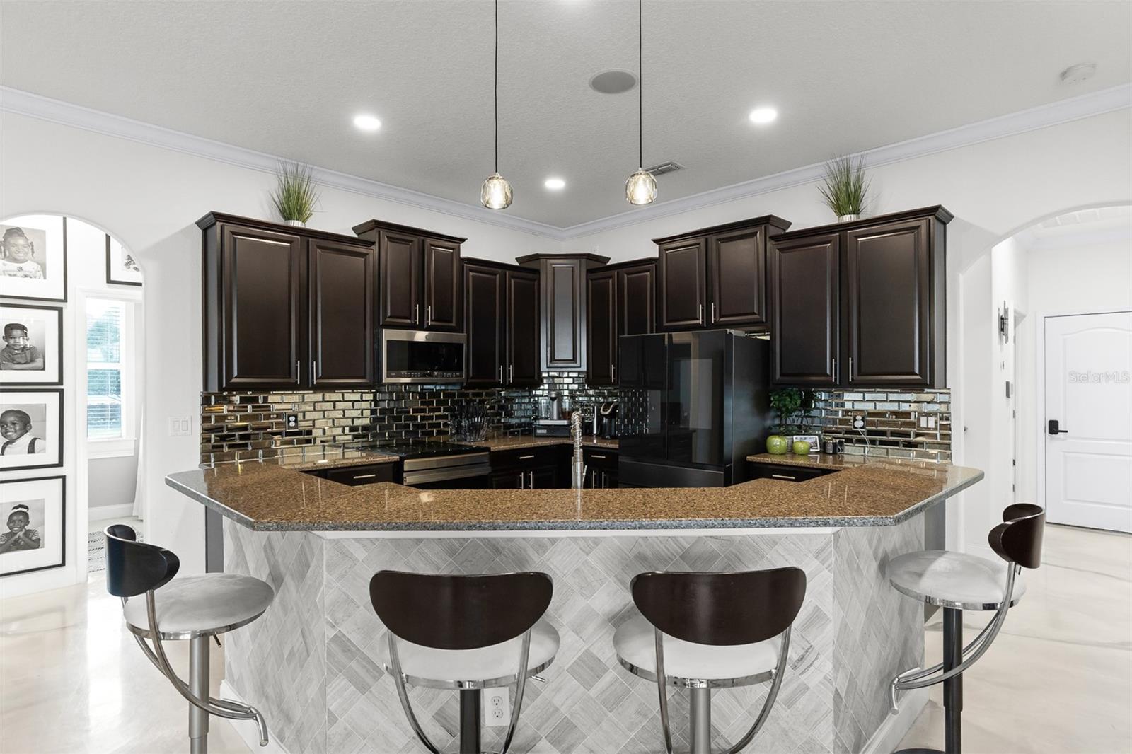 Gourmet kitchen with dark espresso cabinets, metallic tile backsplash, and stone counters.