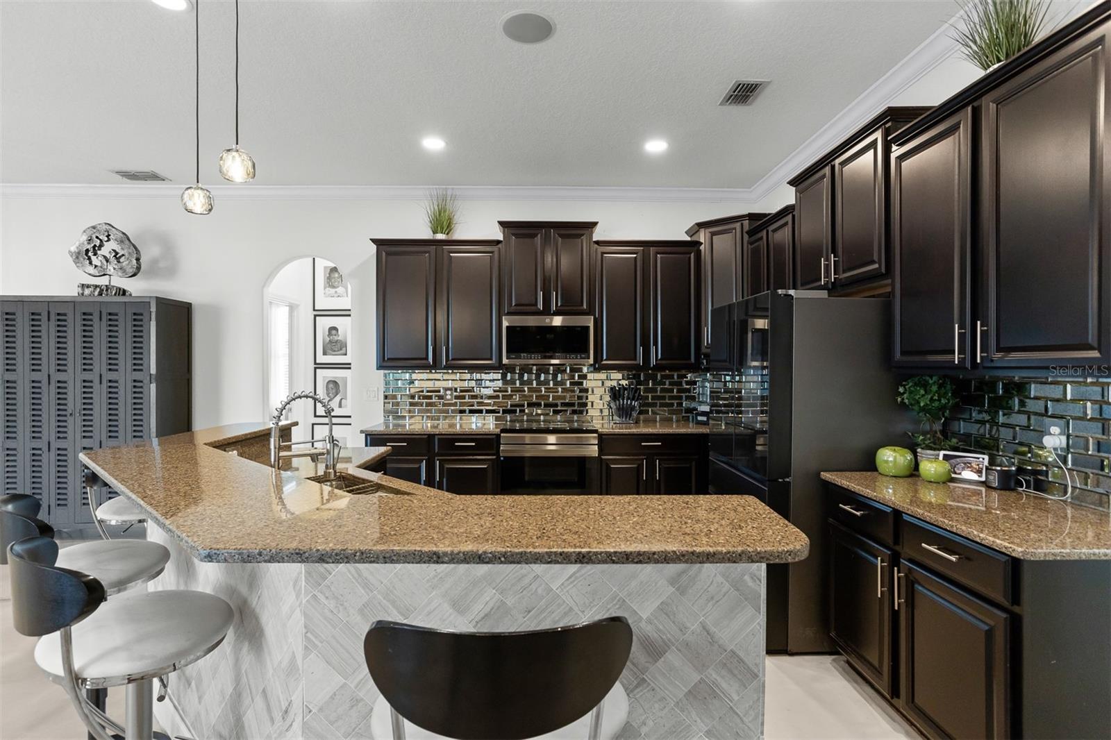 View of the spacious breakfast bar with built-in sink and designer pendant lighting.