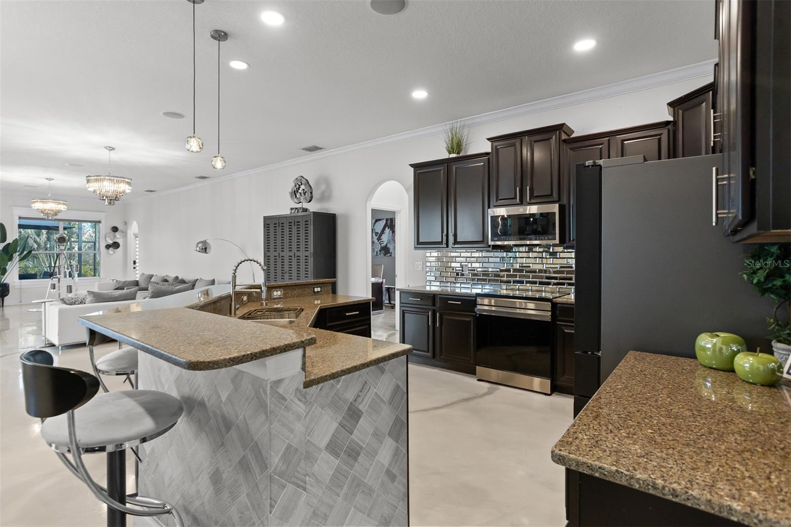 Angled view of the kitchen featuring the breakfast bar, pendant lighting, and high-gloss floors.