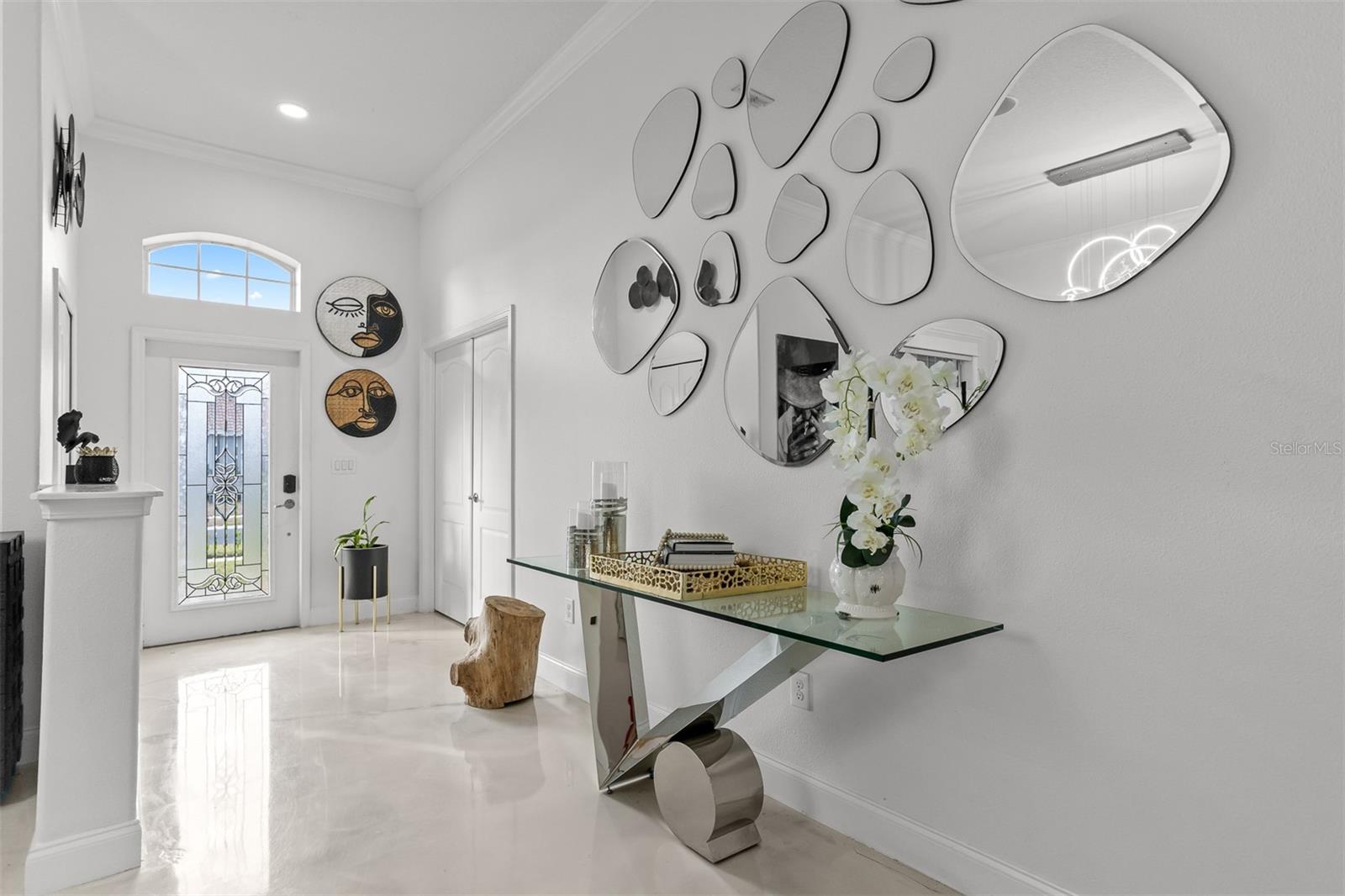 Elegant entryway with a console table, unique pebble-style mirrors, and marble-look flooring.