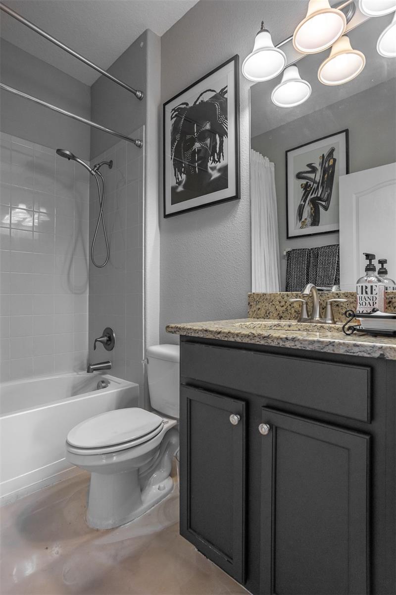 Updated guest bathroom featuring a granite vanity, dark cabinetry, and modern hardware.