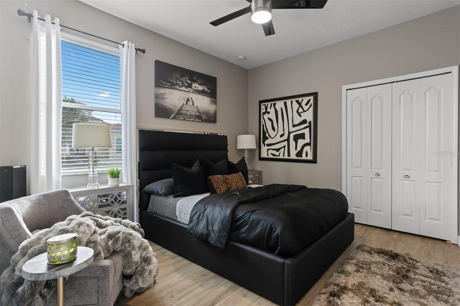 Stylish guest bedroom with dark tufted headboard, luxury bedding, and natural lighting.