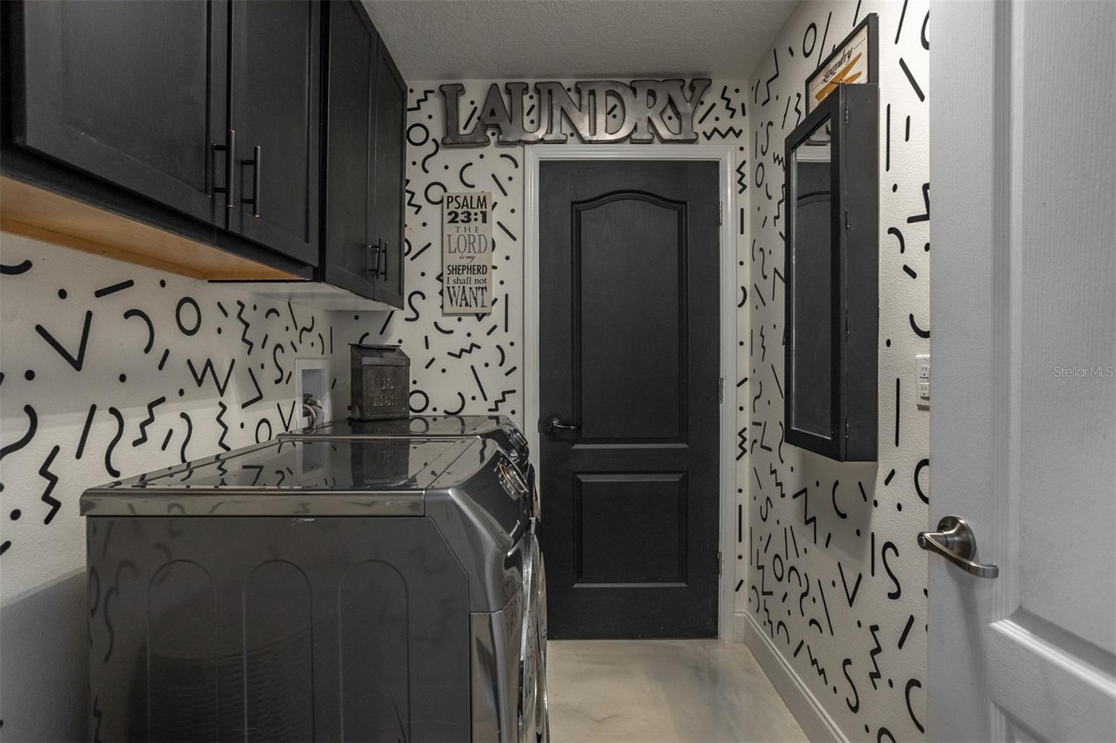 View of laundry room highlighting custom cabinetry, storage, and designer accents.