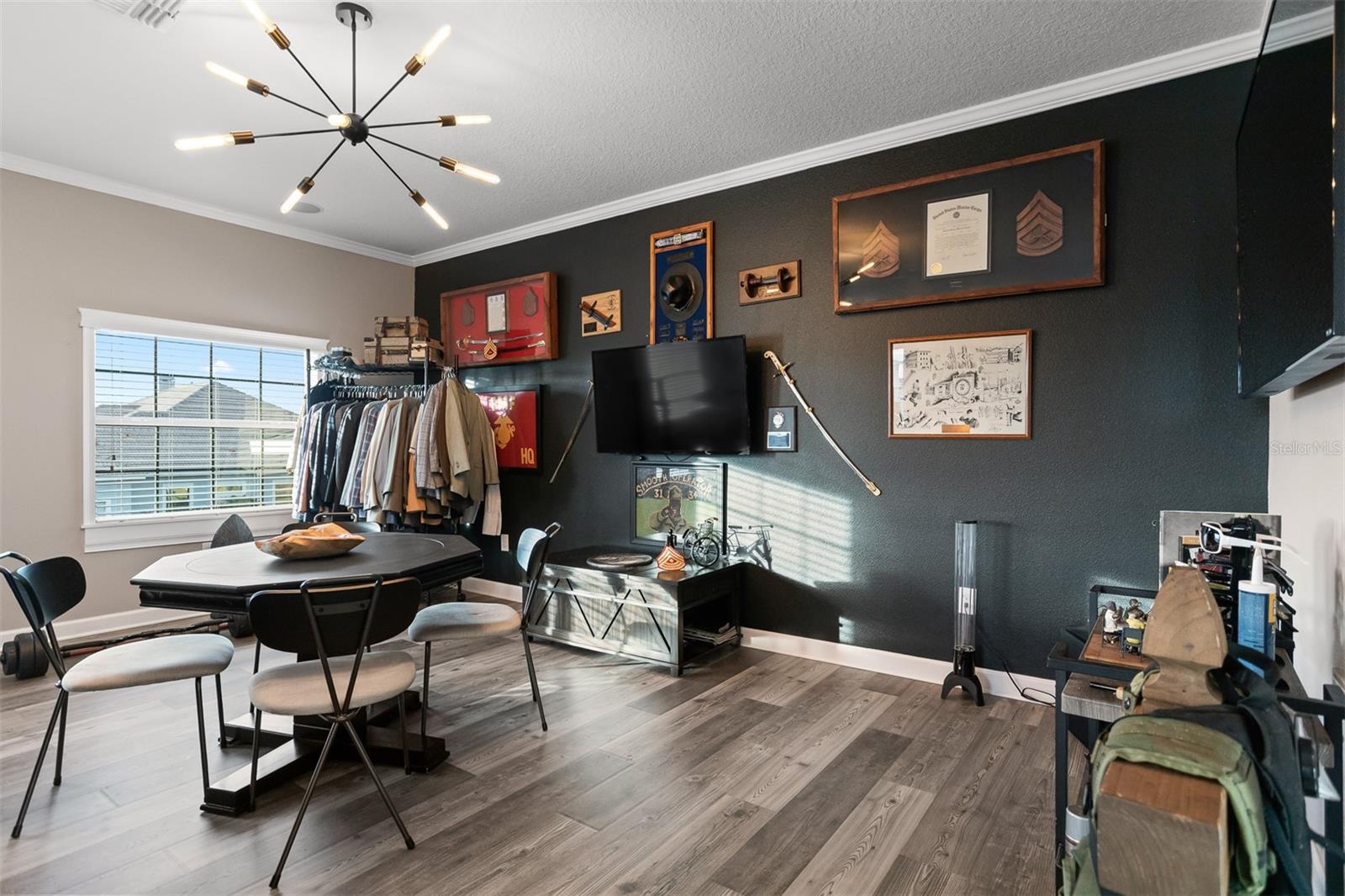 Custom media room/loft with dark accent wall, sputnik lighting, and built-in storage.
