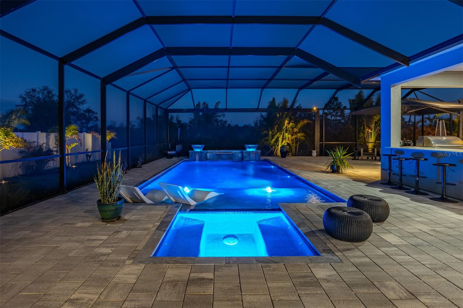 Integrated spa and pool glowing blue against the dark Florida evening sky.