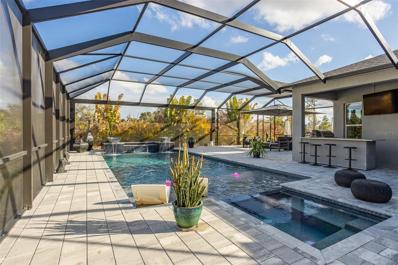 Tropical pool oasis featuring sun shelf loungers and custom waterfall bowls.