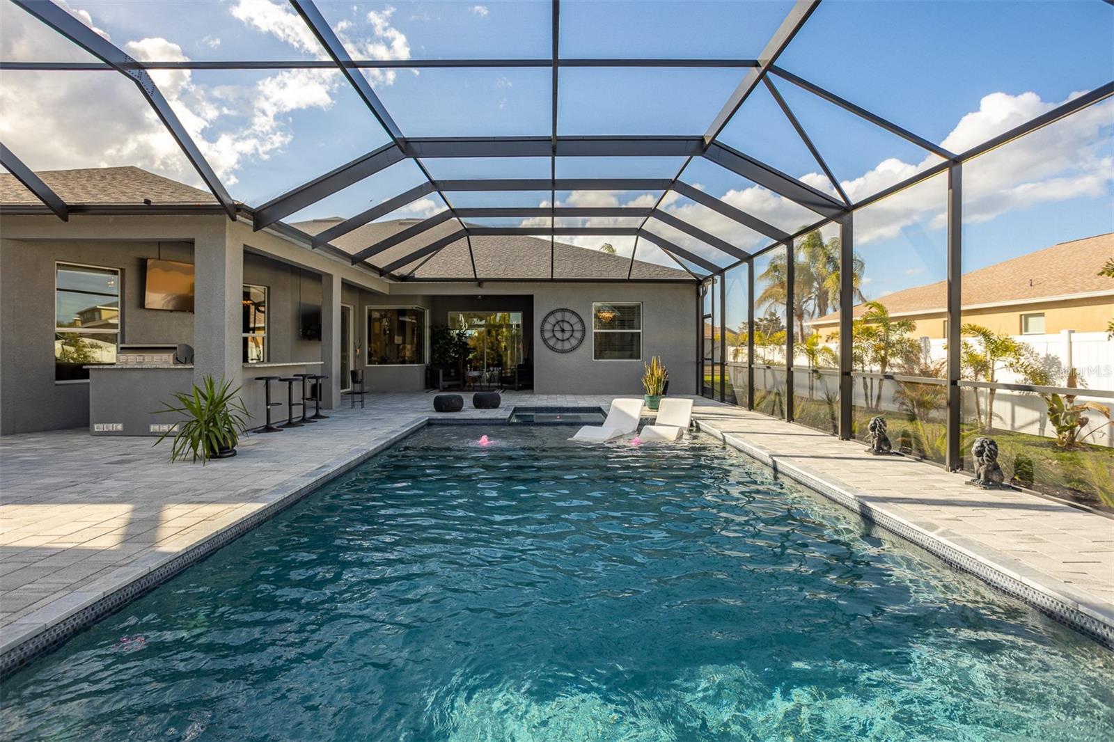 Wide view of the luxury pool area showing the integration with the summer kitchen.