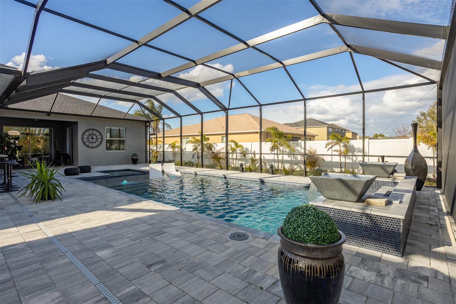 Large custom pool with waterfall bowls and built-in sun shelf.