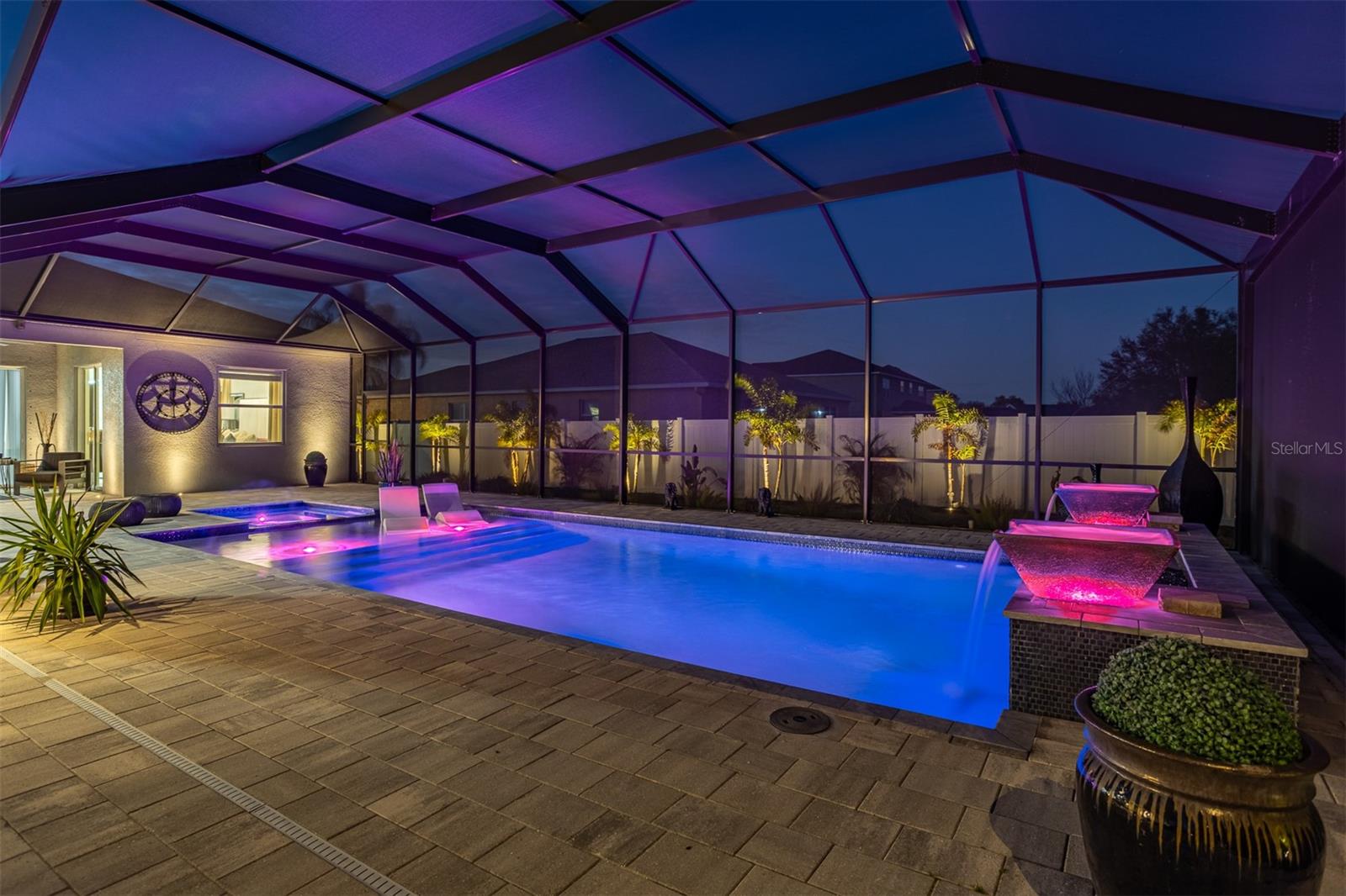Screened-in pool at night featuring vibrant pink and blue LED color-changing lights.