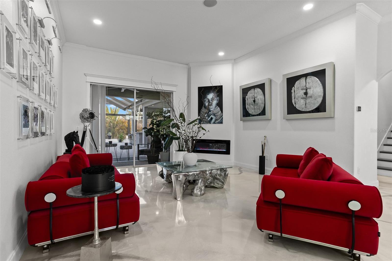 Designer great room featuring high-gloss epoxy floors, an electric fireplace, and red velvet sofas.