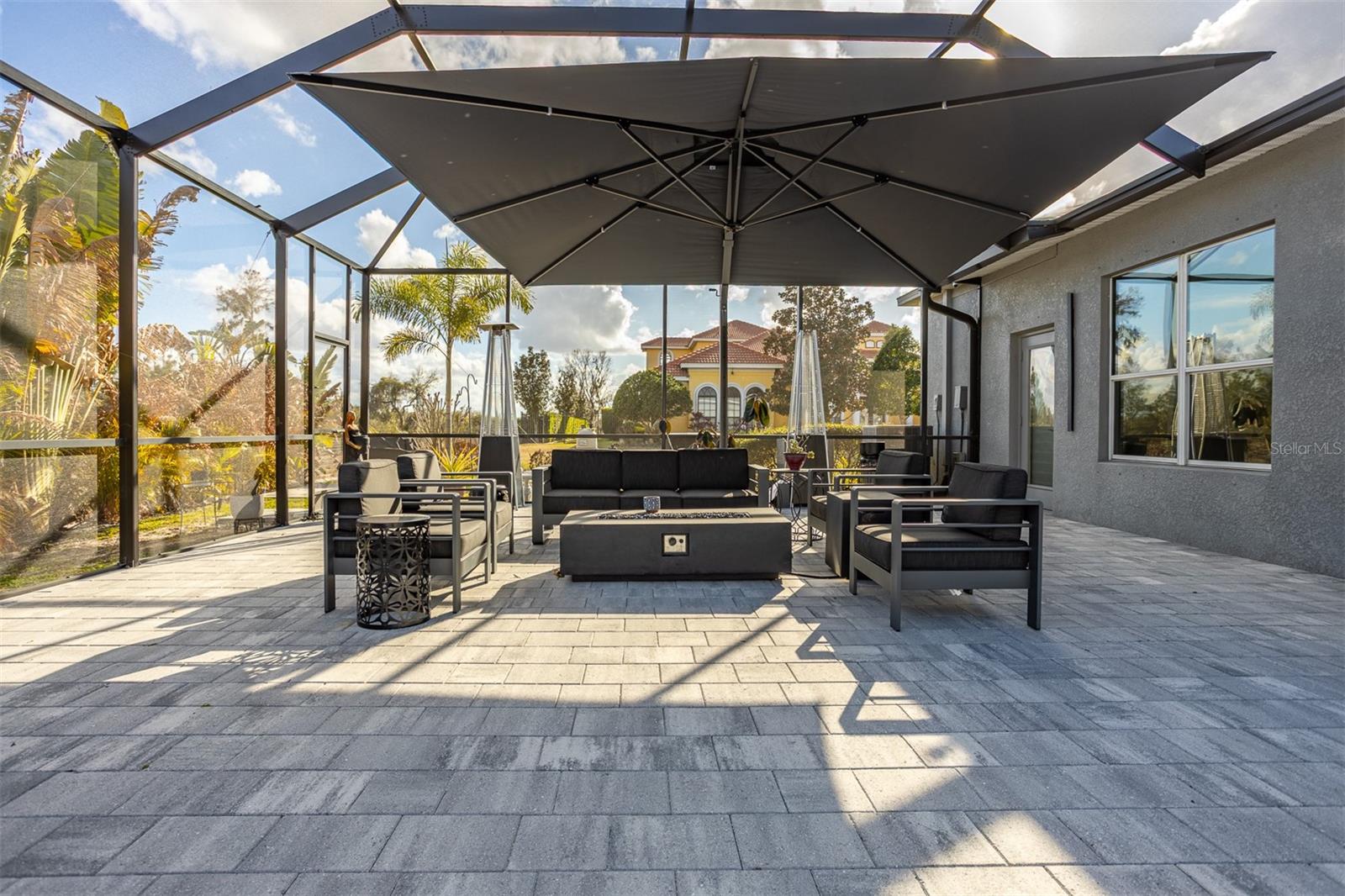 Modern outdoor seating area with gas fire pit and oversized shade umbrella.