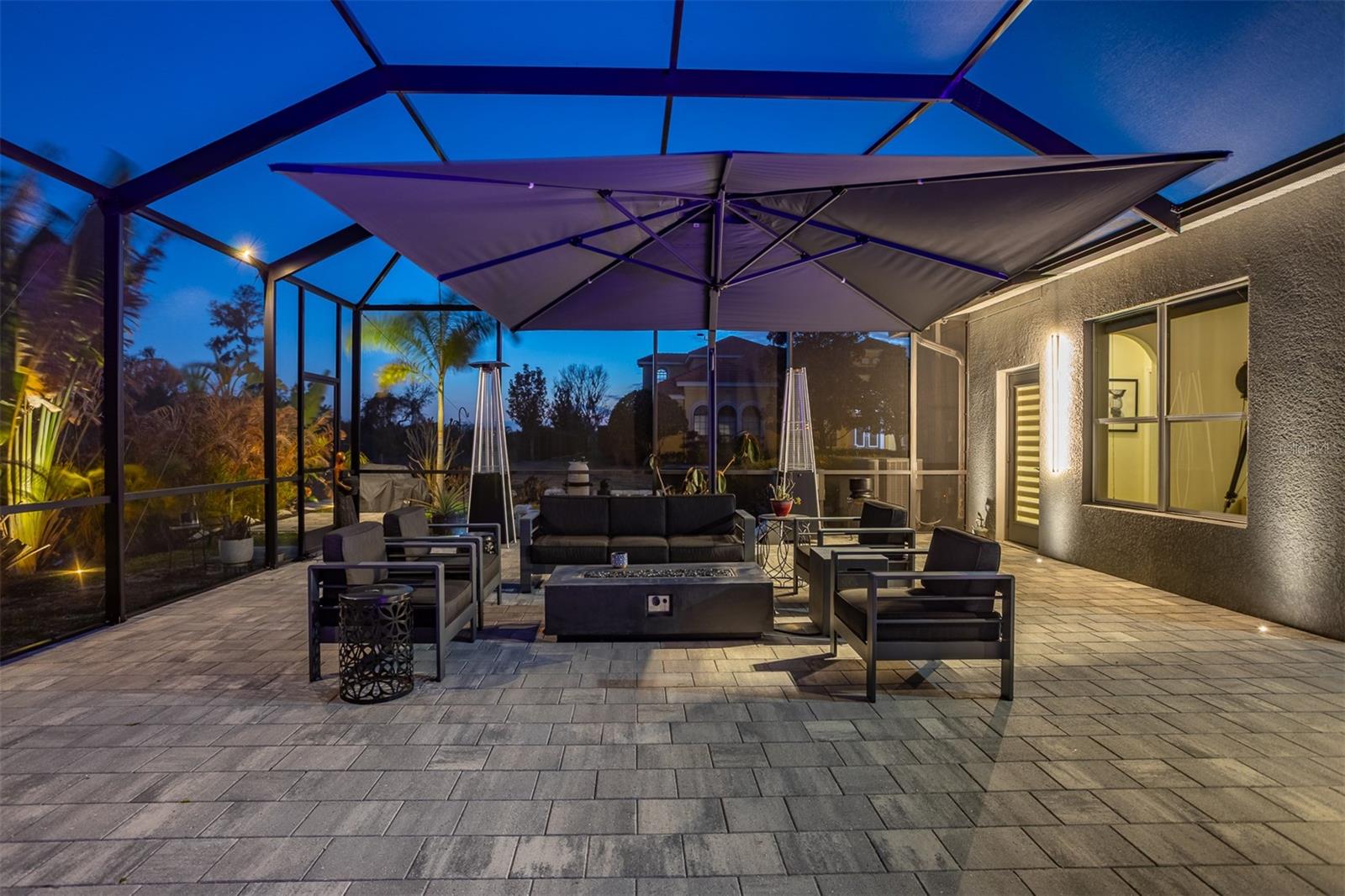 Evening view of the outdoor lounge, fire pit, and summer kitchen under the stars.
