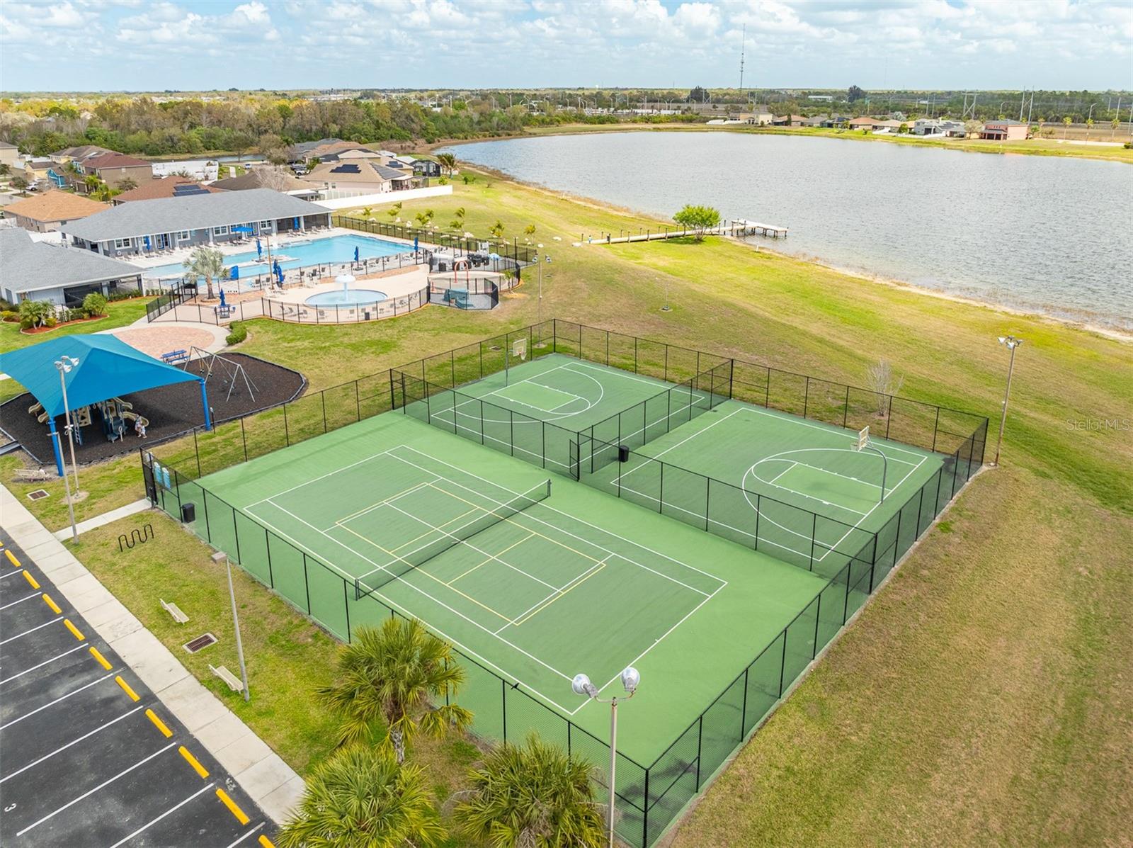Angled view of the sports courts showing the playground and pool in the background.