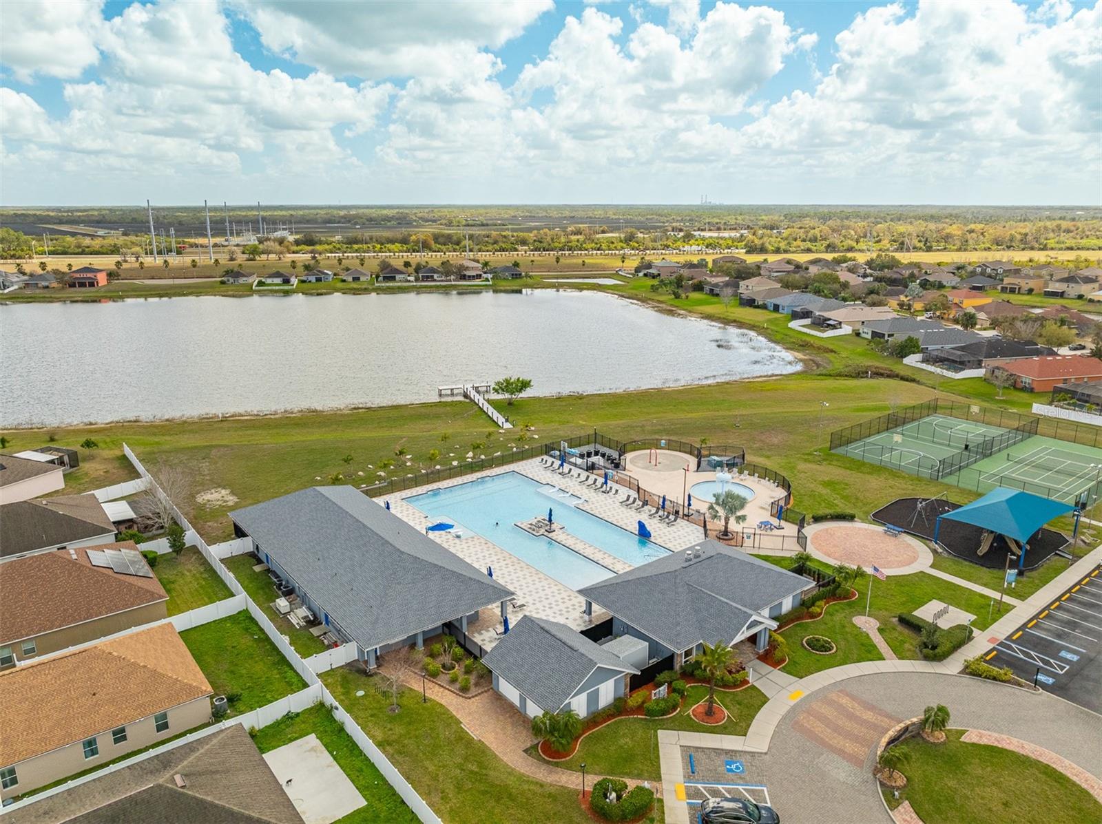 View of the clubhouse entrance and pool area from across the lawn.