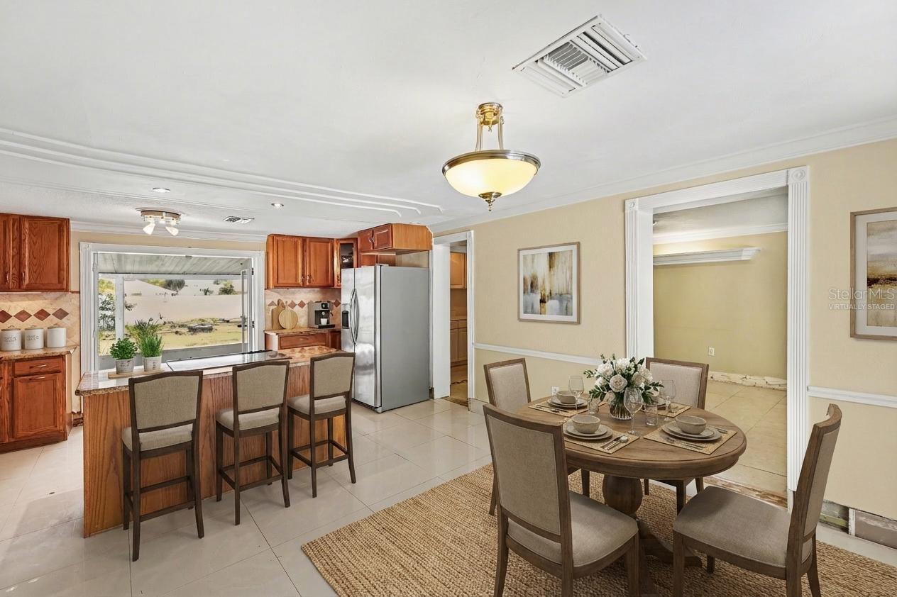 Virtually Staged-Kitchen and dinning room. French glass doors take  you to the spacious screened back lanai.