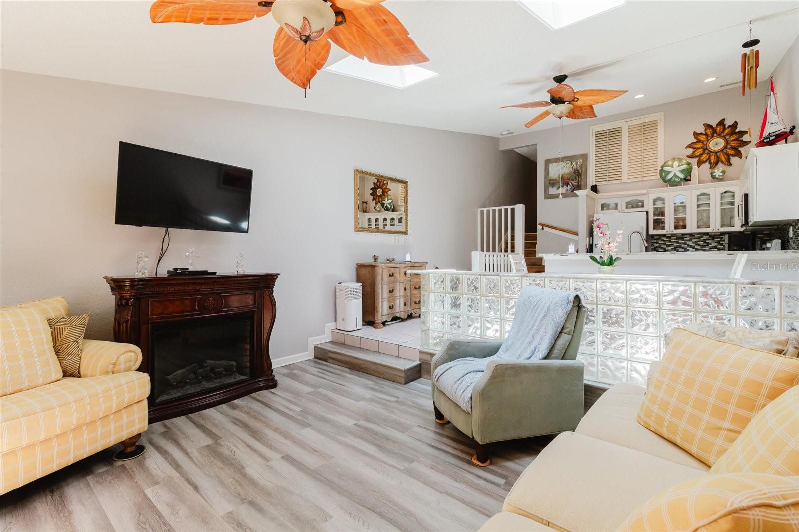 Open Concept Living Room With Luxury Vinyl Floors & Balcony Access. Easy Access to Kitchen. Skylights Provide Natural Signlight In