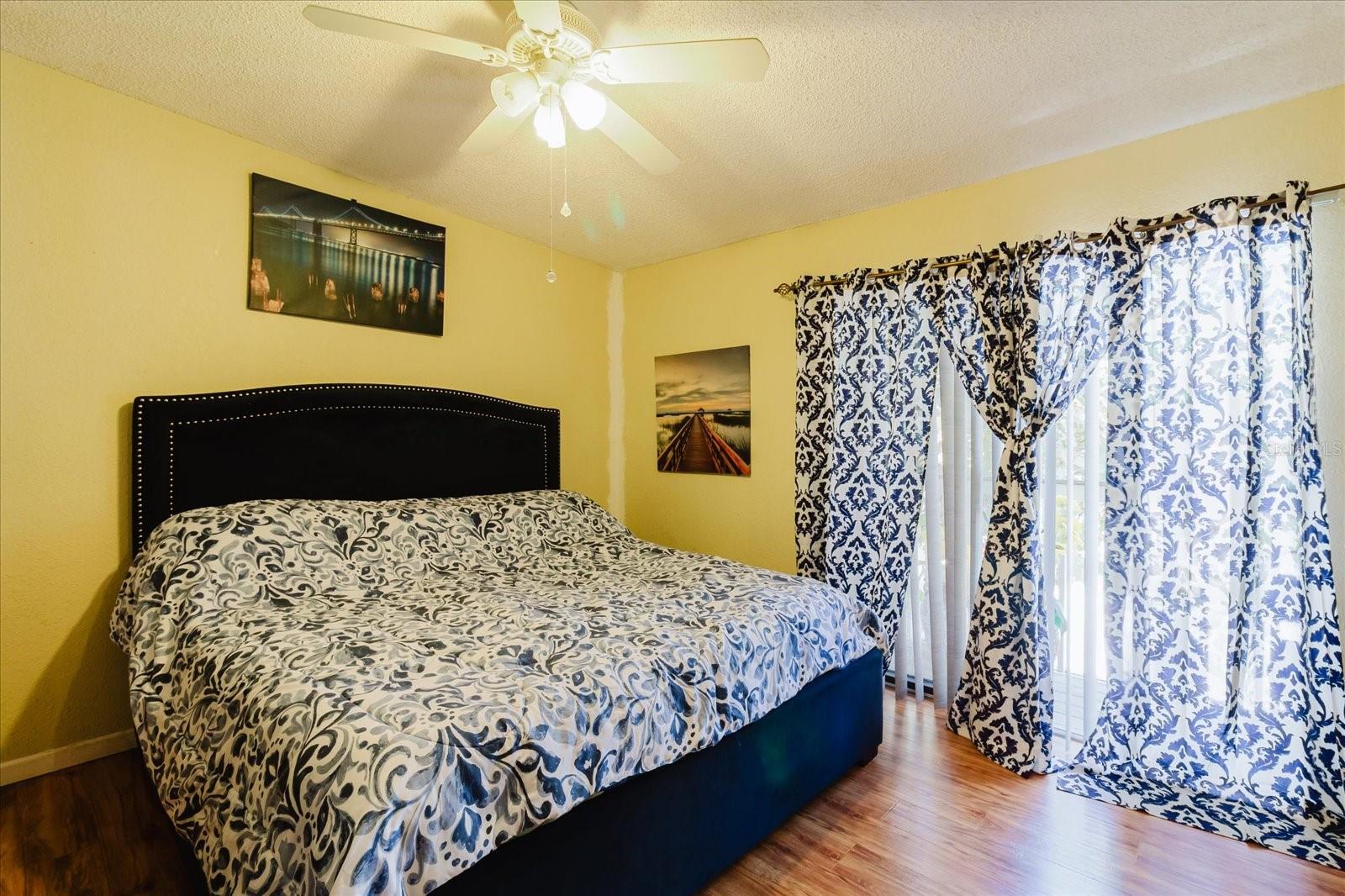 Primary Bedroom Fits A King Size Bed, Luxury Vinyl Flooring. Curtains Covering the Balcony.
