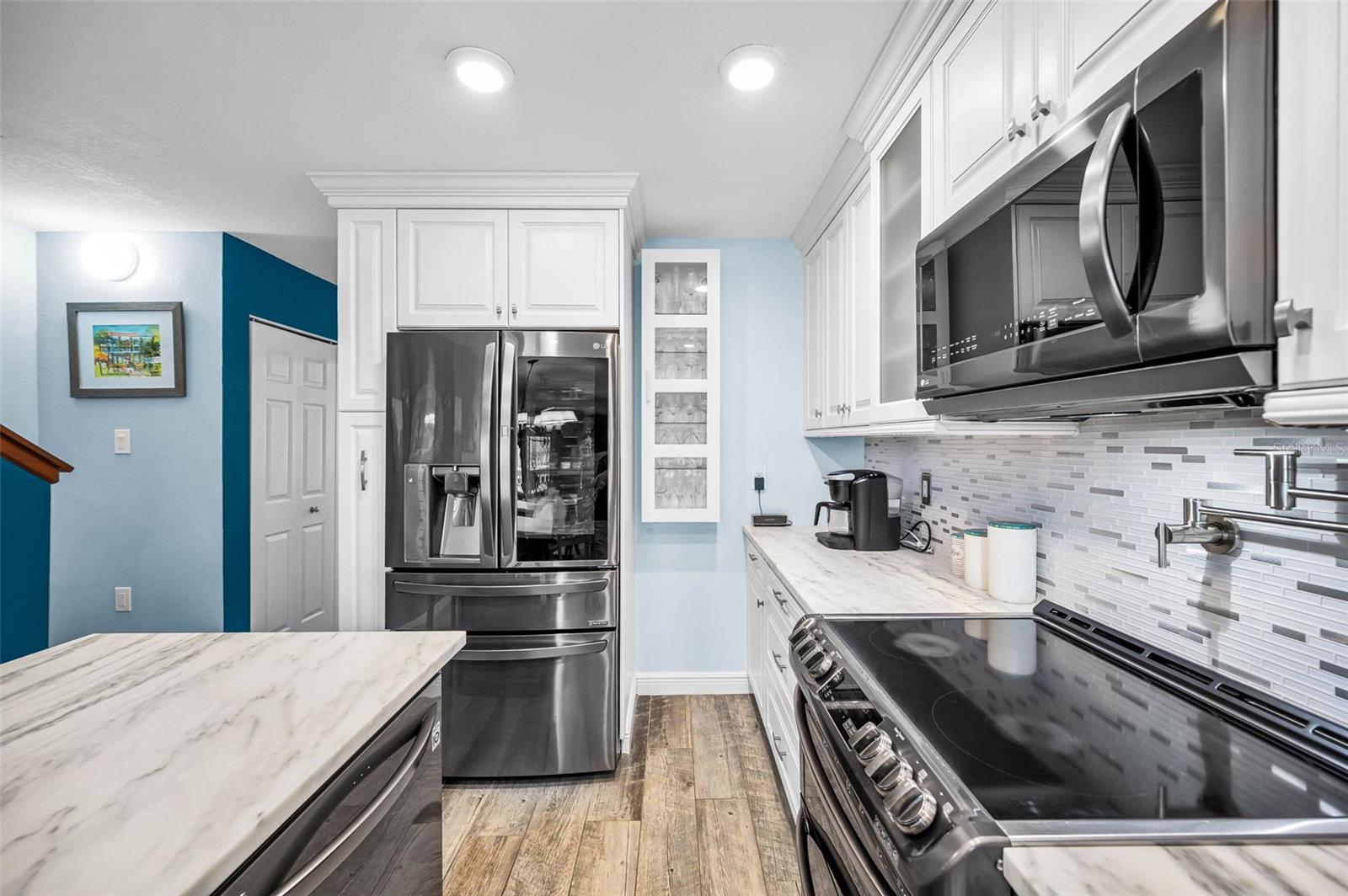 Refined glass-panel cabinetry, marble countertops and subway tile backsplash that elevates the kitchen’s coastal-contemporary aesthetic