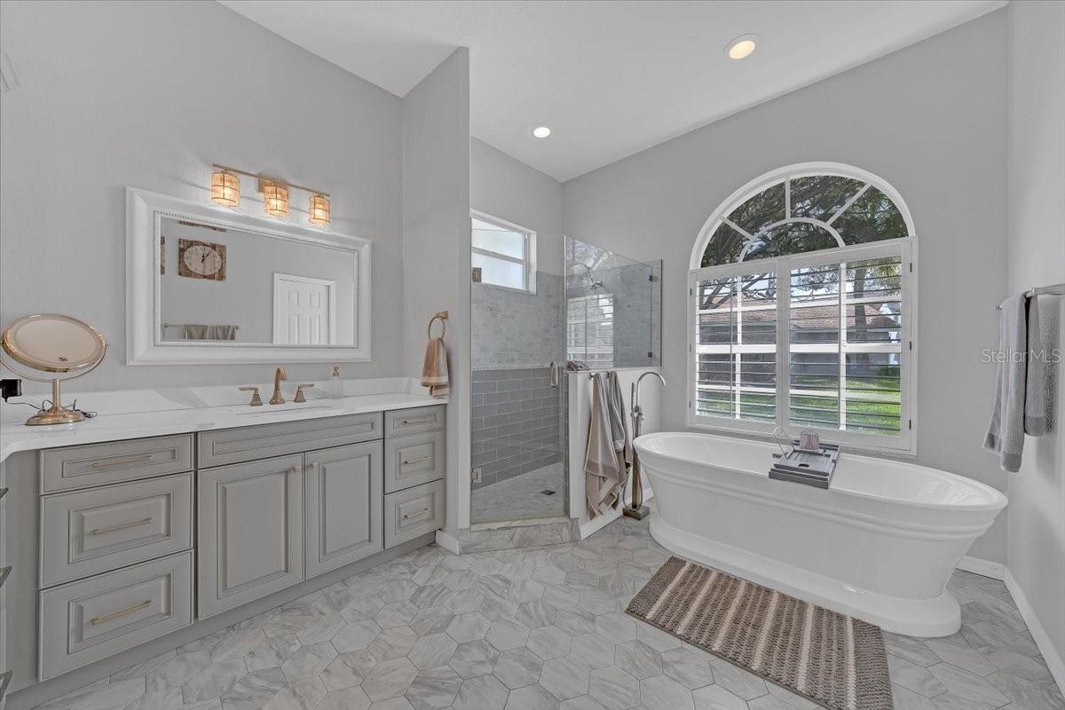 En-suite bathroom featuring tub, vanity and shower area.